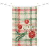 Blood Orange & Olive Plaid Christmas tea towel, sliced blood oranges and an olive sprig on red and sage green plaid, hanging in a kitchen