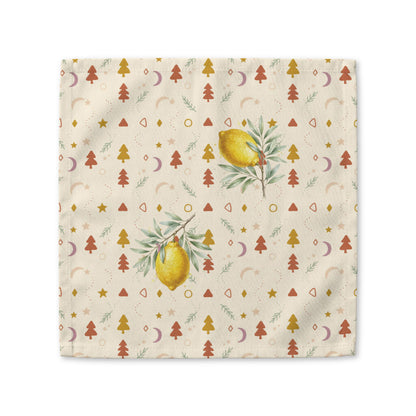 Lemon and pine Christmas cloth napkin laid flat, with watercolour lemons among small rust and gold Christmas trees, stars and crescent moons on cream