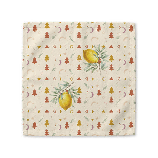 Lemon and pine Christmas cloth napkin laid flat, with watercolour lemons among small rust and gold Christmas trees, stars and crescent moons on cream