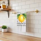 Limoncello tea towel hanging from a brass rail against white subway tile