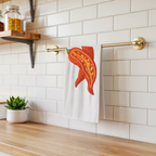 Chili Pepper tea towel hanging from a brass rail against white subway tile