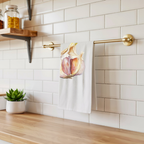 Garlic tea towel hanging from a brass rail against white subway tile