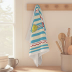 Limoncello Amore Mio tea towel hanging from a peg rail beside a window, with wooden utensils and stacked bowls