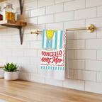 Limoncello Amore Mio tea towel hanging from a brass rail against white subway tile