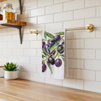Olive Branch tea towel hanging from a brass rail against white subway tile