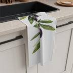 Olive Branch tea towel draped over the edge of a kitchen cabinet