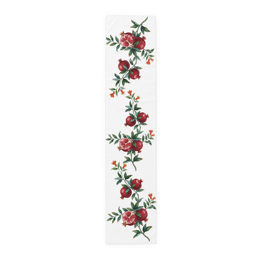 Pomegranate table runner in polyester, 16 by 72 inches, laid flat with repeating pomegranate branches and red blossom