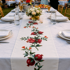 Pomegranate table runner down a long white banquet table set with flowers
