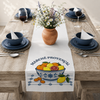 Marché Provençal table runner on a laid table with dark plates and a terracotta pot of white flowers