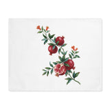 Pomegranate placemat laid flat, showing a watercolor pomegranate branch with red blossom on white cotton twill