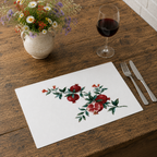 Pomegranate placemat on a wooden table with cutlery, a glass of red wine and a stone jug of wildflowers