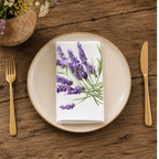 Lavender napkin folded on a cream plate between gold cutlery, beside a terracotta vase of Mediterranean wildflowers