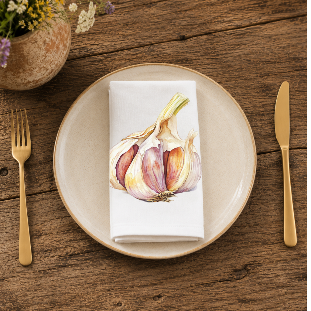 Garlic napkin folded on a cream plate between gold cutlery, beside a terracotta vase of Mediterranean wildflowers