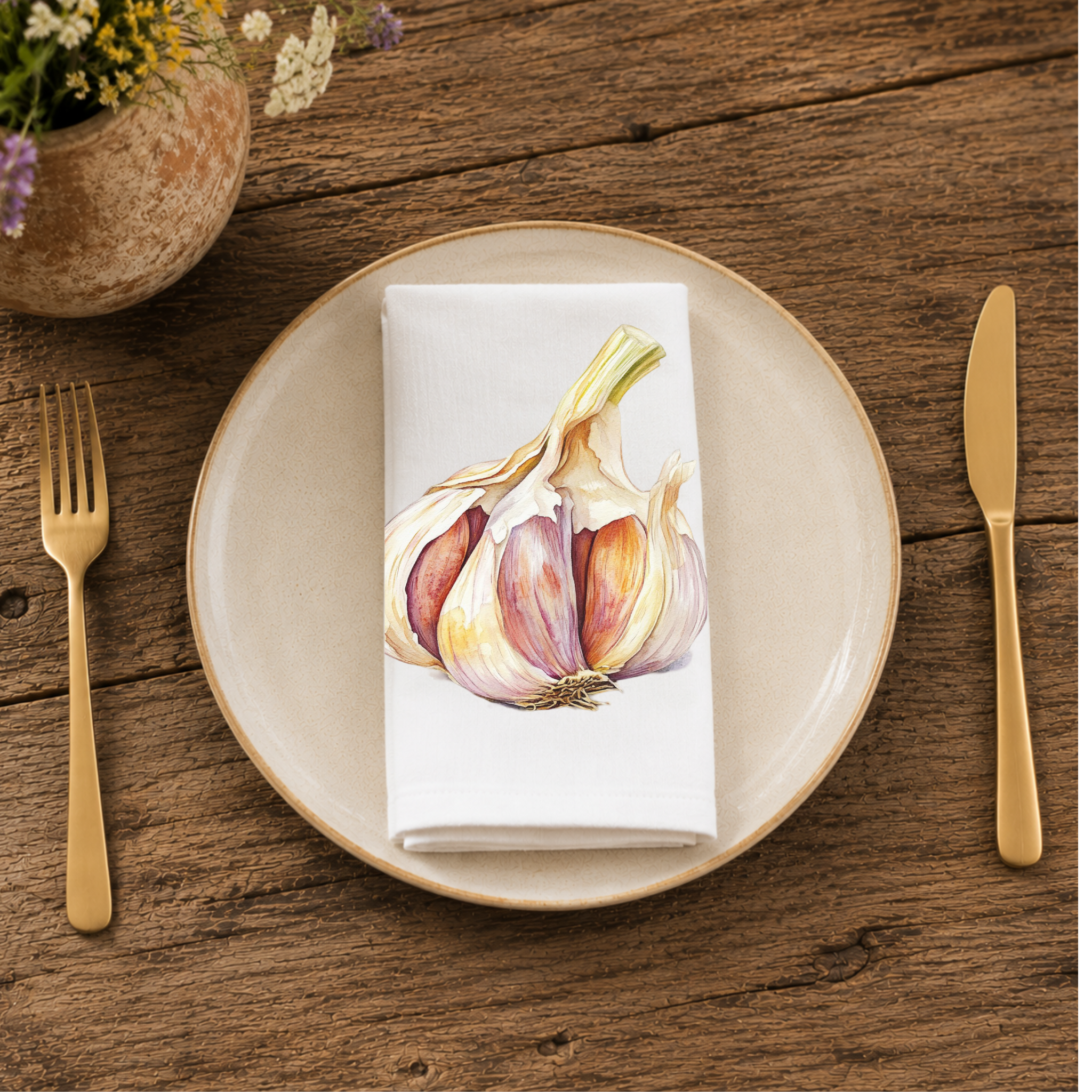 Garlic napkin folded on a cream plate between gold cutlery, beside a terracotta vase of Mediterranean wildflowers