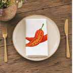 Chili Pepper napkin folded on a cream plate, beside a terracotta vase of Mediterranean wildflowers