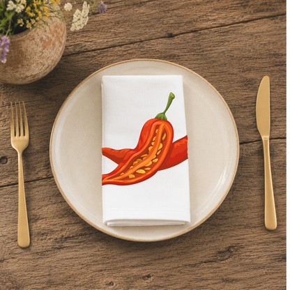 Chili Pepper napkin folded on a cream plate, beside a terracotta vase of Mediterranean wildflowers