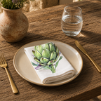 Artichoke napkin on a cream plate with a glass of water and a terracotta vase of Mediterranean wildflowers
