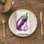 Eggplant and Garlic napkin folded on a cream plate between gold cutlery, beside a terracotta vase of Mediterranean wildflowers