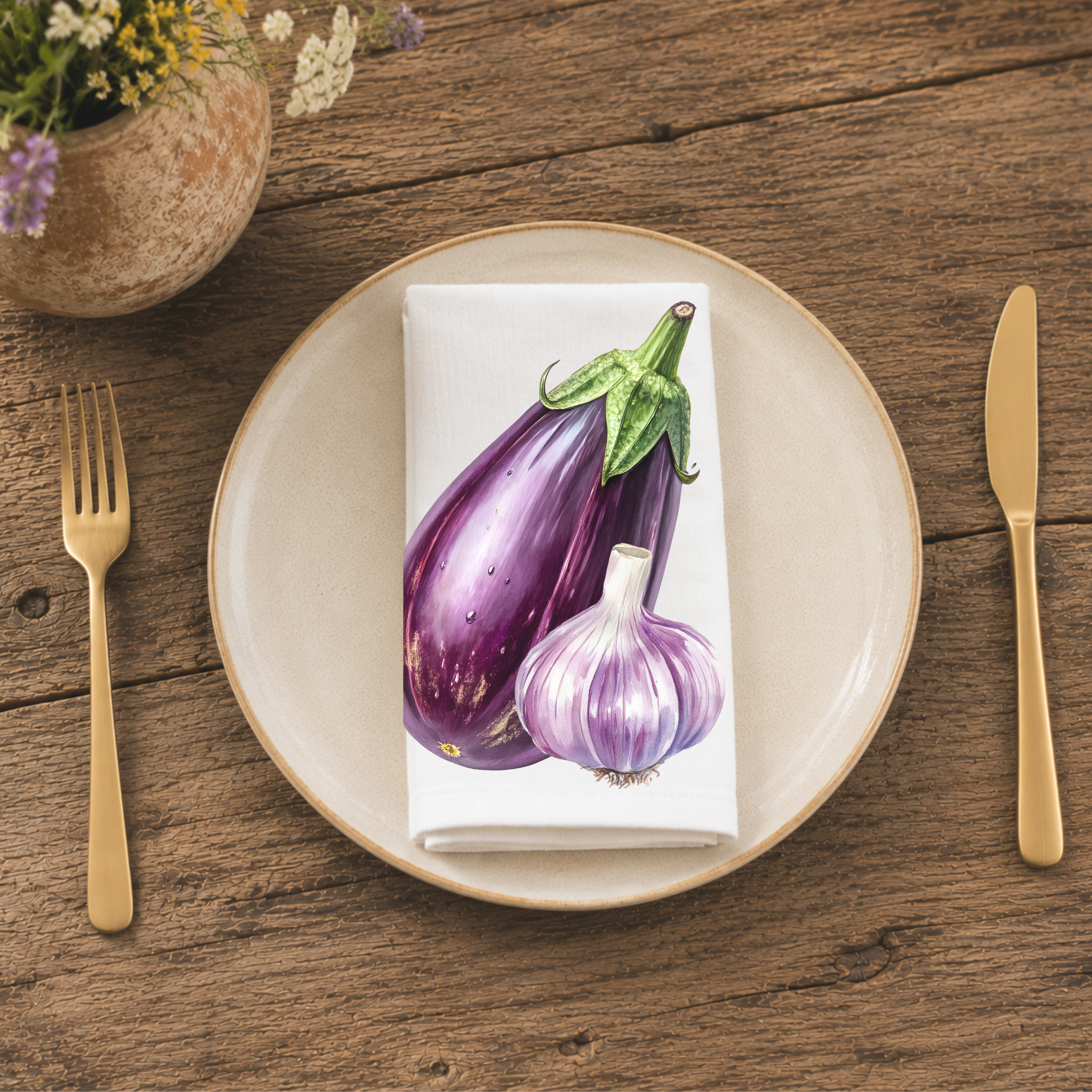 Eggplant and Garlic napkin folded on a cream plate between gold cutlery, beside a terracotta vase of Mediterranean wildflowers