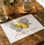 Amalfi Summer placemat on a dark wooden table with cutlery and a terracotta pot of greenery