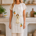 Woman wearing the Angels and oranges Christmas apron in a light Mediterranean kitchen