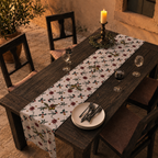Poinsettia and olive Christmas table runner on an outdoor wood table at dusk, lit by a single candle