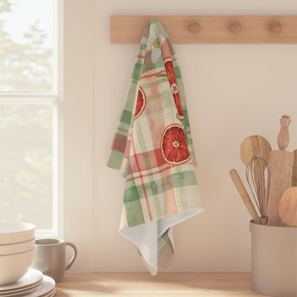 Blood Orange & Olive Plaid Christmas tea towel, an olive sprig and orange blossom on the plaid, folded on a counter