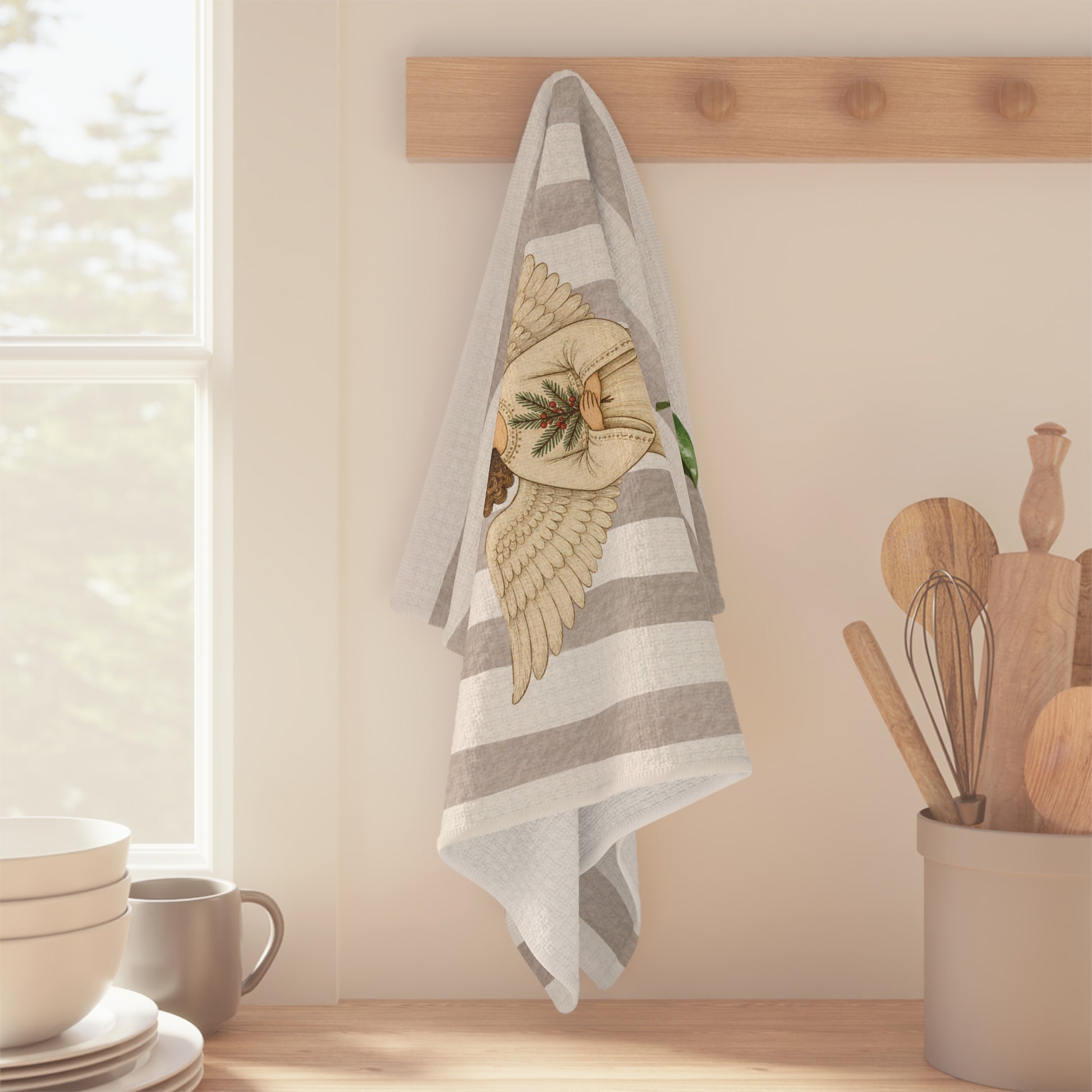 Angels and oranges Christmas tea towel hanging from a wooden peg rail beside a sunlit kitchen window