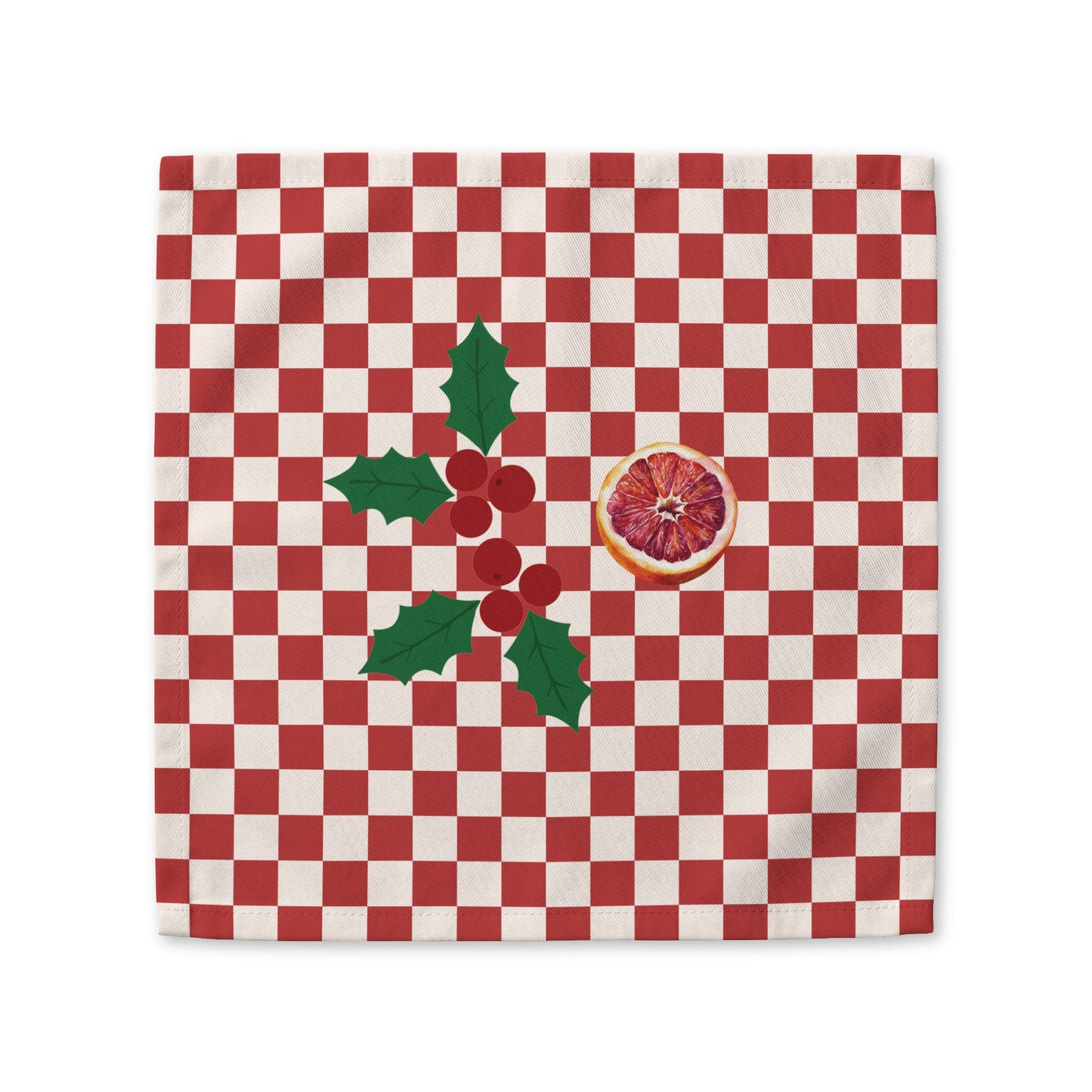 Blood orange check Christmas cloth napkin laid flat, a red and cream checkerboard with holly and a cut blood orange