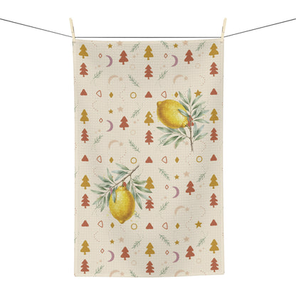 Lemon and pine Christmas tea towel shown flat, with watercolour lemons among small rust and gold Christmas trees, stars and crescent moons on cream