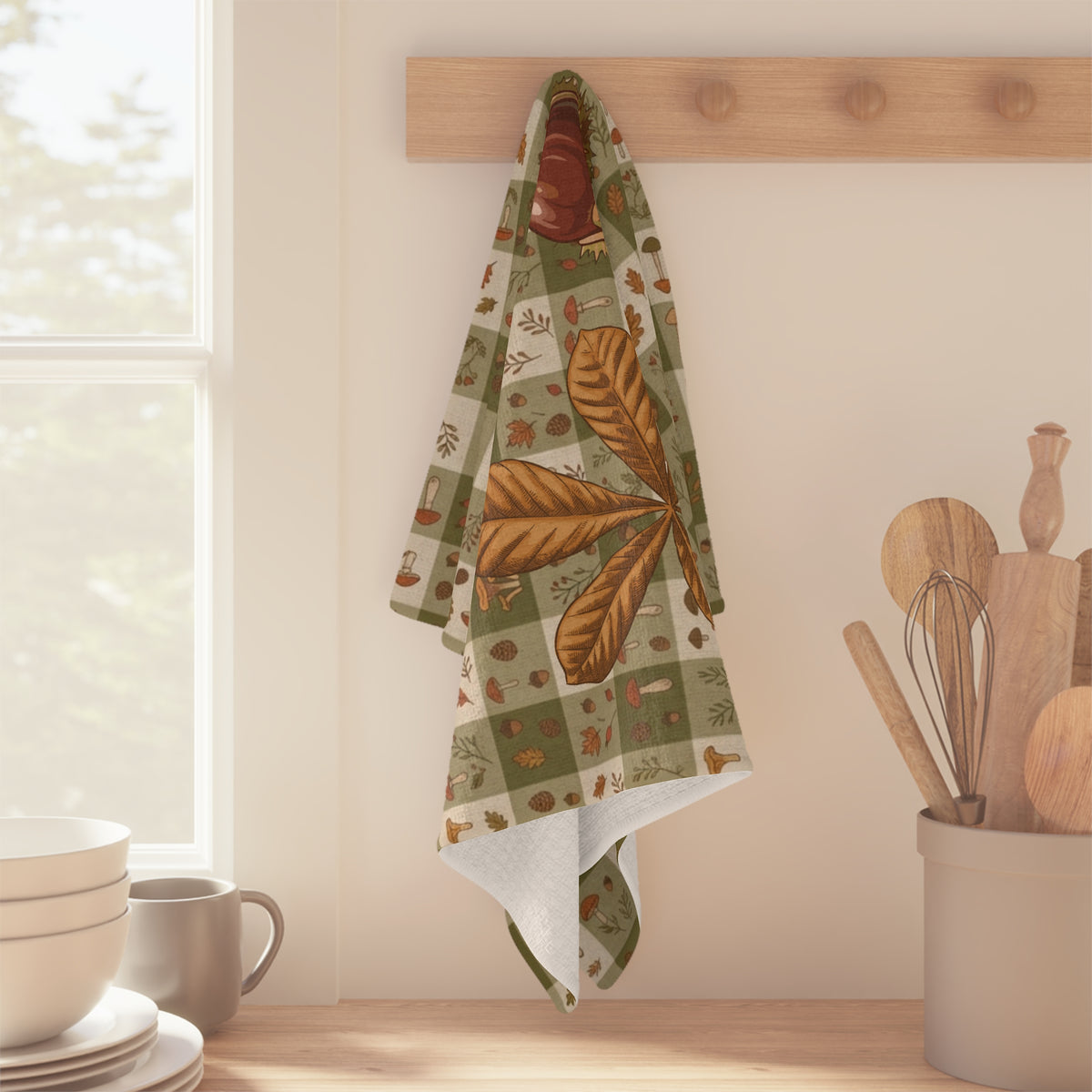 Chestnut & Mushroom fall tea towel, acorns and autumn leaves on a green check, folded on a counter
