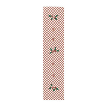 Blood orange check Christmas table runner laid flat, a red and cream checkerboard with holly and a cut blood orange