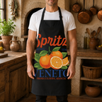 Black Spritz Veneto apron worn in a rustic kitchen with copper pans and hanging herbs