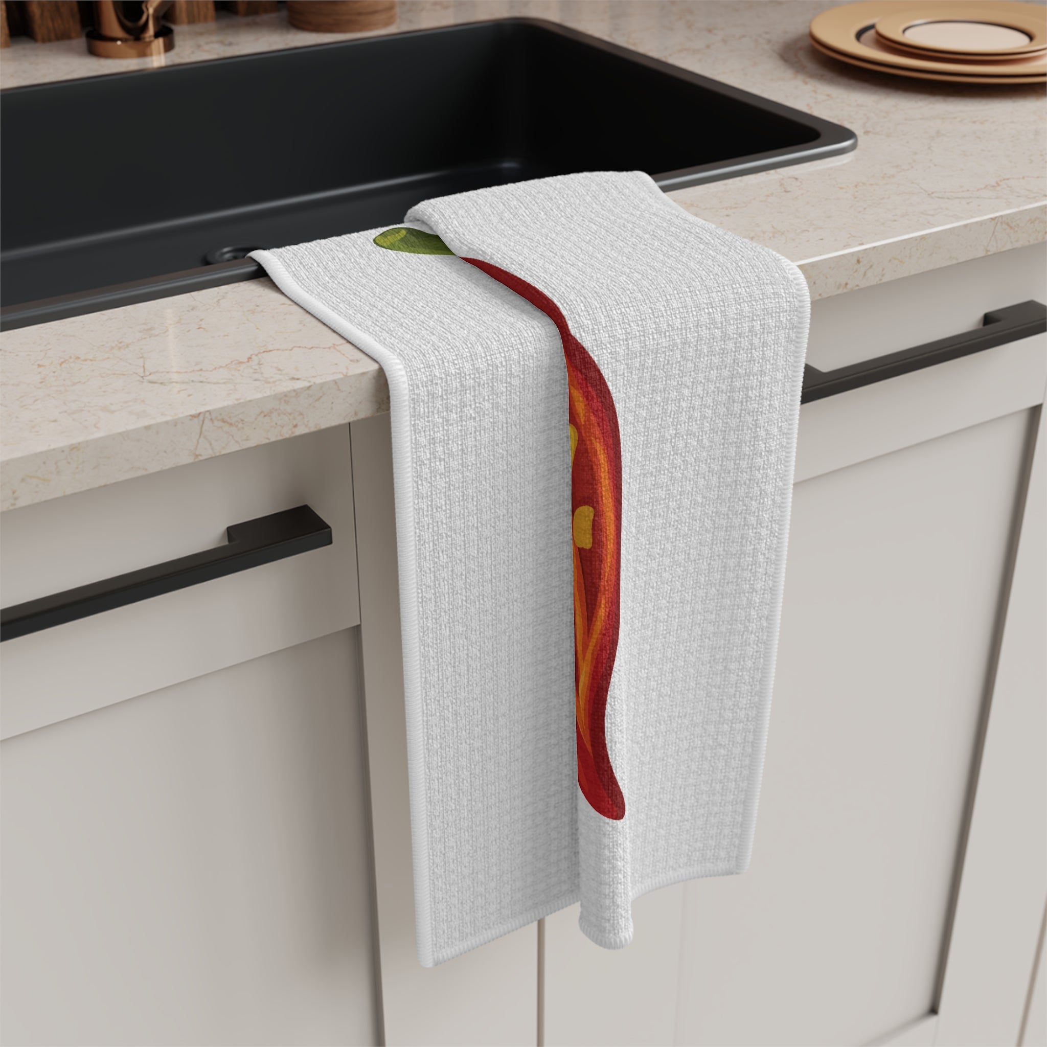 Chili Pepper tea towel draped over the edge of a kitchen cabinet