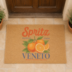 Spritz Veneto coir doormat on stone paving in front of a weathered wooden door, with potted herbs on either side