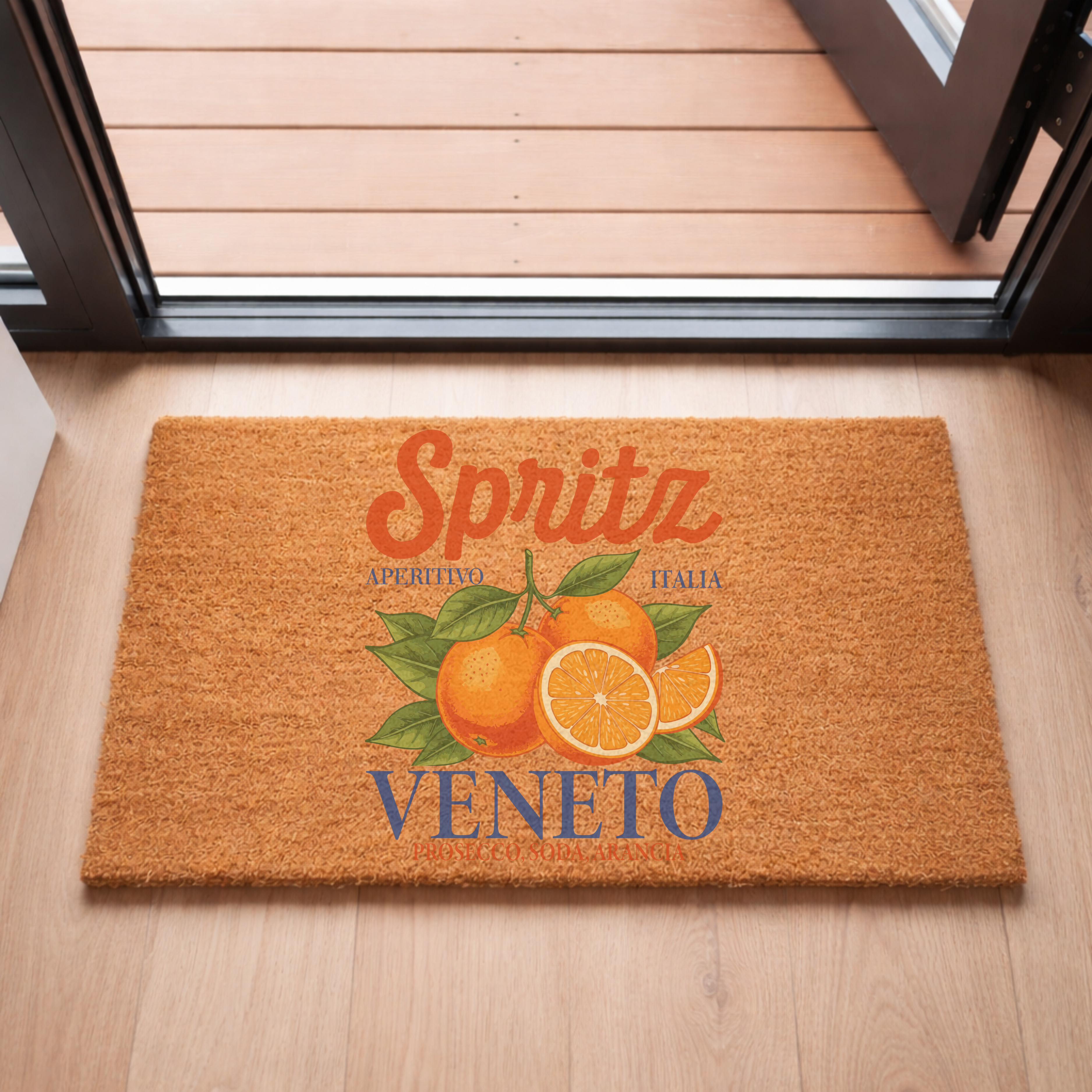 Spritz Veneto coir doormat on a light wooden floor inside an open sliding door, with a decked terrace beyond