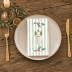 Angels and holly napkin folded on a stoneware plate, seen from above with gold cutlery and a brass candlestick