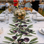 Olive Branch table runner down a long white banquet table set with flowers and glasses