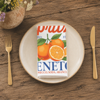 Spritz Veneto cloth napkin folded on a stoneware plate, seen from above with gold cutlery and a pot of wildflowers on a wooden table