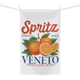 Spritz Veneto tea towel hanging from a clothesline by two wooden pegs, showing the full Spritz Veneto label print with oranges on a white waffle weave